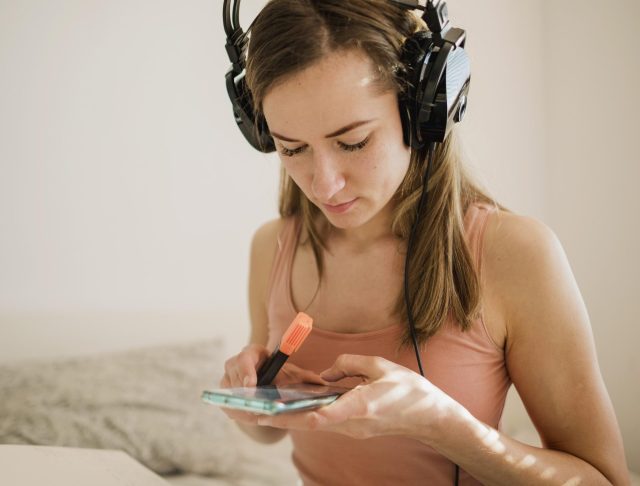 Woman with headphones holding smartphone